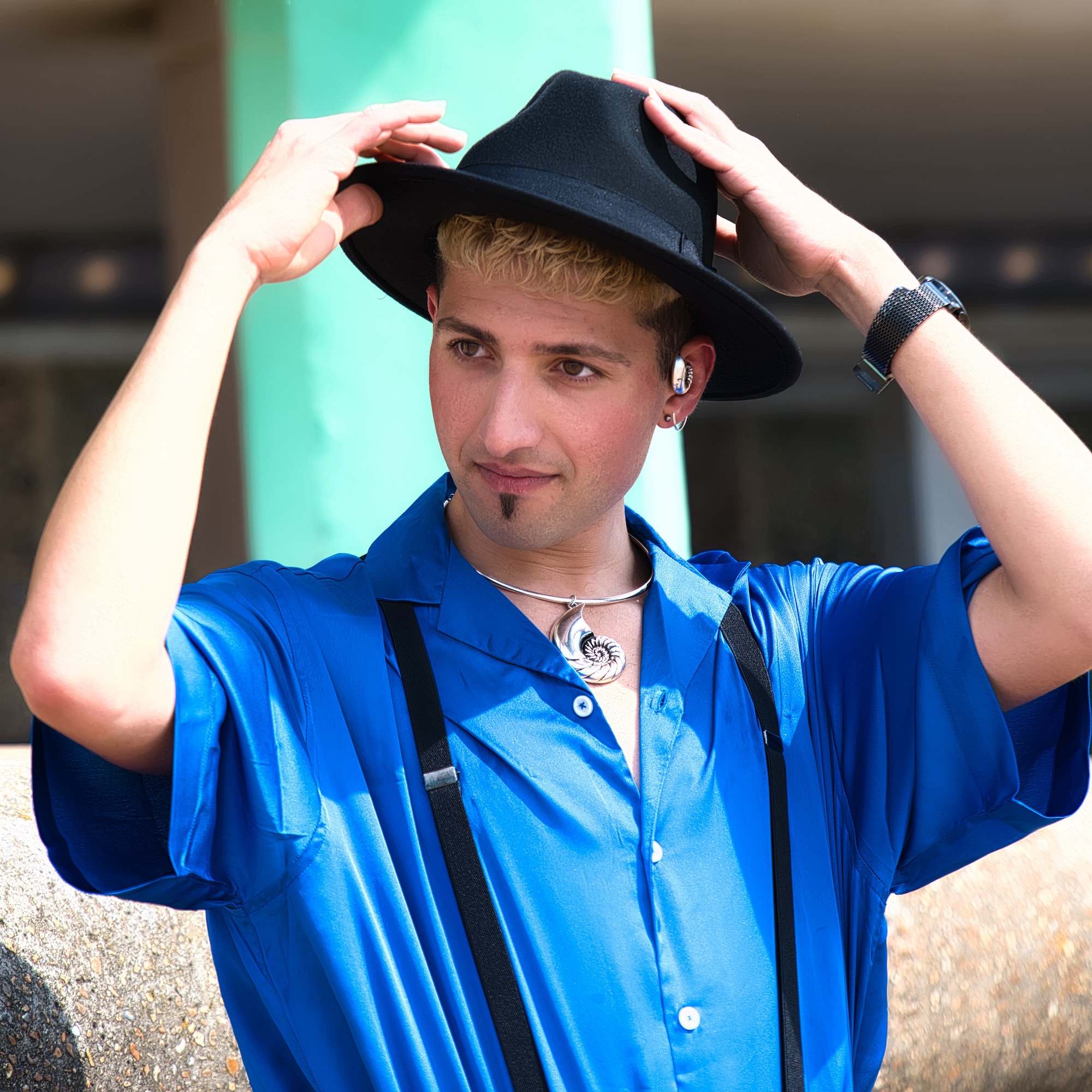 colour upper torso image of a young man adjusting his hat