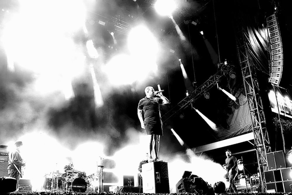 Mike Smith of the Streets standing on a monitor on stage singing