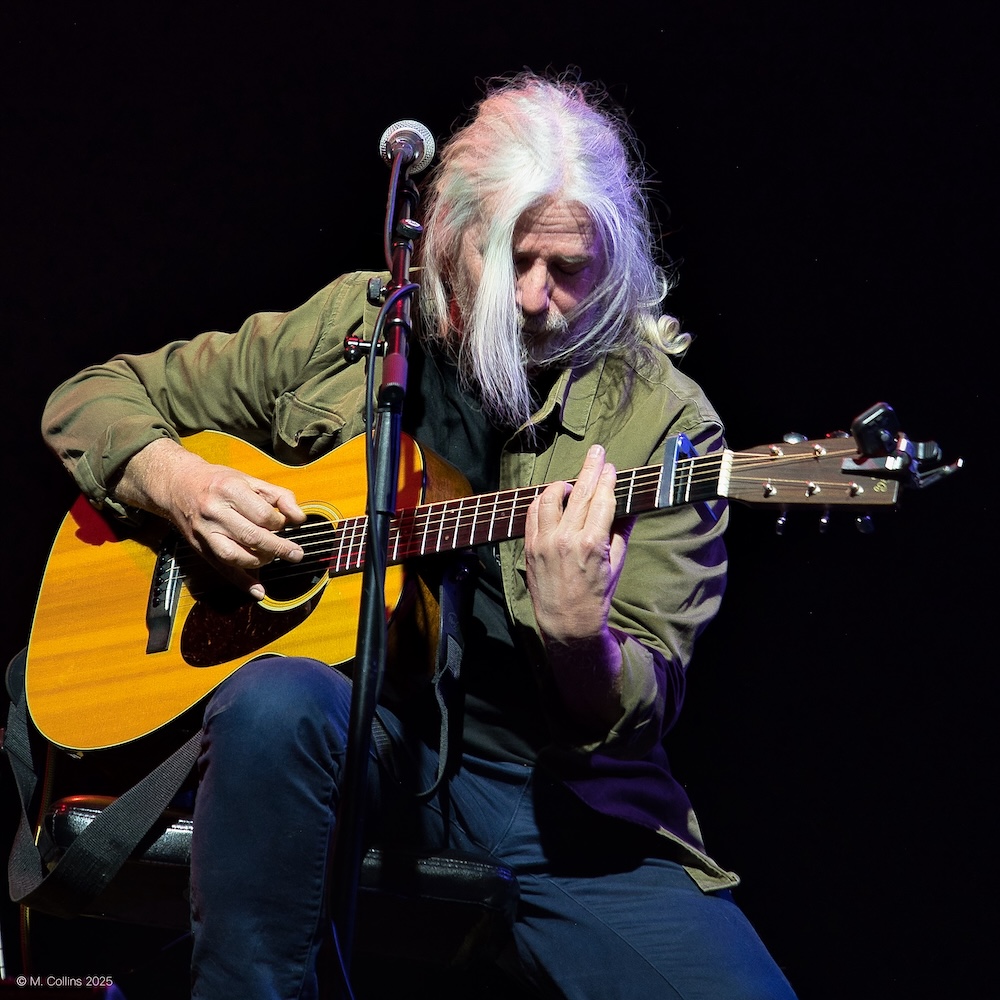 John Branwell playing an acoustic guitar on stage
